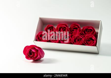 Boîte avec roses rouges décoratives sur un fond blanc isolé. Banque D'Images