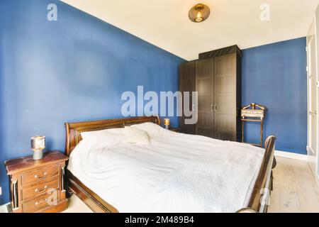 une chambre avec des murs bleus et un lit blanc s'étend sur la pièce, alors qu'elle n'est pas utilisée ou utilisée Banque D'Images