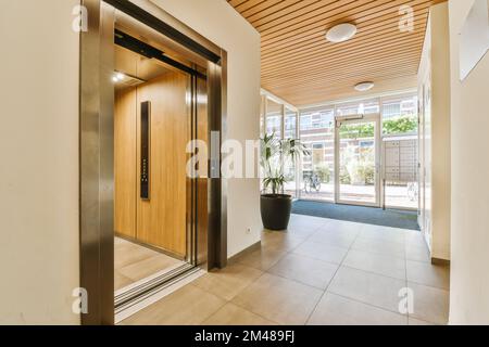 une entrée avec des plafonds en bois et des portes vitrées menant à l'entrée de cette maison moderne et lumineuse Banque D'Images