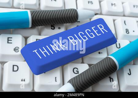 Écriture affichage du texte pensez plus grand. Le concept d'entreprise étant capable de rêver et de visualiser ce que vous pouvez réaliser Banque D'Images