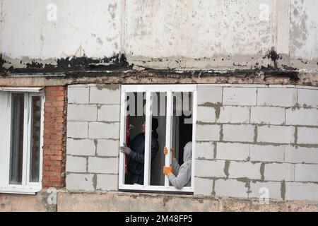 Tiraspol, Moldavie - 6 décembre 2022: Travailleur à l'aide d'un niveau rouge, vérifie l'installation correcte du cadre d'une fenêtre en plastique. Installer Banque D'Images