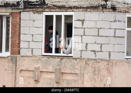 Tiraspol, Moldavie - 6 décembre 2022: Travailleur à l'aide d'un niveau rouge, vérifie l'installation correcte du cadre d'une fenêtre en plastique. Installer Banque D'Images