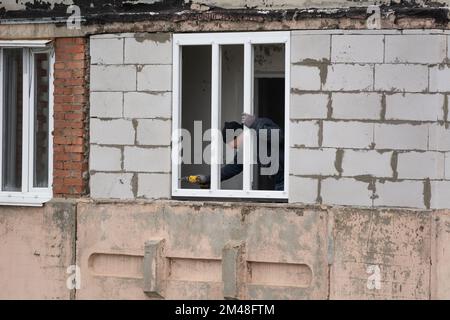 Tiraspol, Moldova - 6 décembre 2022: Installation de fenêtres en plastique. L'employé fixe le cadre de la fenêtre à l'aide d'un tournevis. Installation de la fenêtre en plastique Banque D'Images