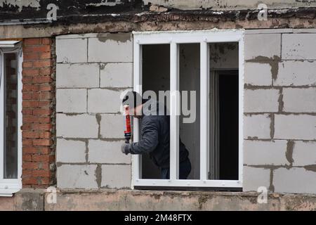 Tiraspol, Moldova - 6 décembre 2022: Le travailleur applique de la mousse de polyuréthane pour combler l'espace entre la ceinture et le cadre de la fenêtre. Créer le confort et le confort pour Banque D'Images