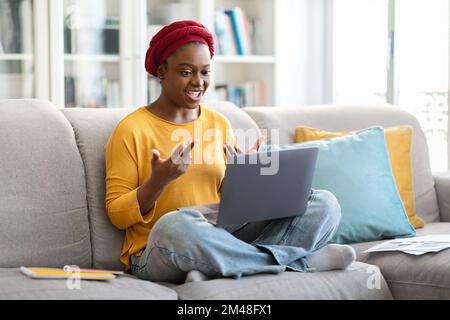 Femme noire travaillant à la maison, ayant des visioconférences avec des collègues Banque D'Images