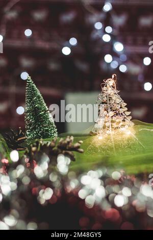 Carte de Noël et du nouvel an avec un petit arbre vert artificiel et des cônes sur une table avec un fond coloré dans lequel les lumières brillent, créant un bok Banque D'Images