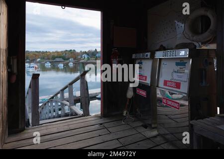 Pompes à carburant dans un sac en bois sur la jetée de Rockport Marine sur la côte du Maine, avec une vue à travers la porte des bateaux amarrés dans la baie Banque D'Images