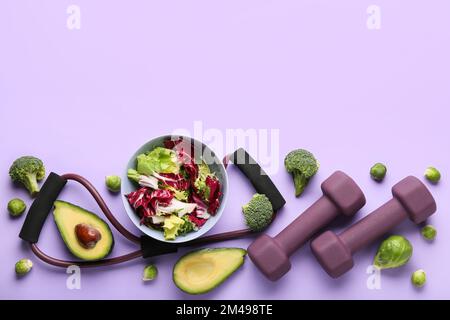 Bol avec salade de légumes, haltères et expandeur sur fond de couleur Banque D'Images