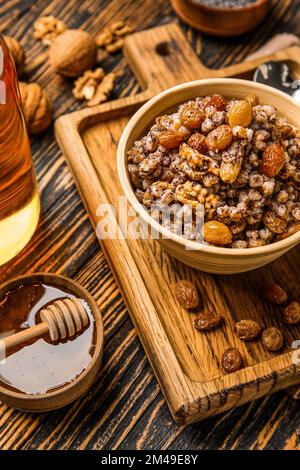 Bol de Kutya avec raisins secs et miel sur fond de bois, gros plan Banque D'Images