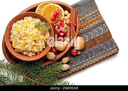 Plateau avec bol de riz Kutya, ingrédients et branches de Noël sur fond blanc Banque D'Images