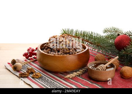 Bol de Kutya, miel, noix et branches de Noël sur table sur fond blanc Banque D'Images