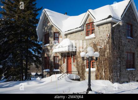 Maison de style cottage en pierre grise et terre cuite recouverte de vignes en hiver. Banque D'Images
