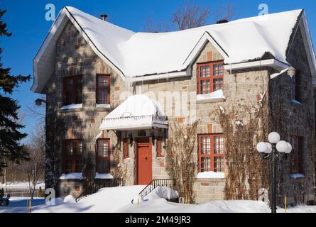 Maison de style cottage en pierre grise et terre cuite recouverte de vignes en hiver. Banque D'Images