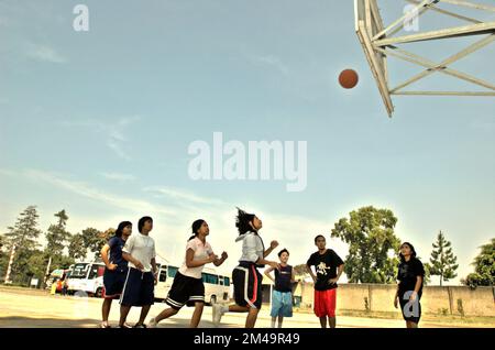 Des adolescents jouant au basket-ball sur un terrain de basket-ball qui, de temps en temps, fonctionnait également comme un parking pour les bus transportant des touristes à Gegerkalong, Bandung, West Java, Indonésie. Banque D'Images