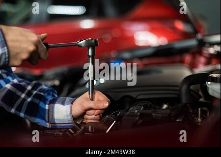 Mécanique automobile femelle en dévissant un écrou pour remplacer une bougie d'allumage de voiture. Banque D'Images