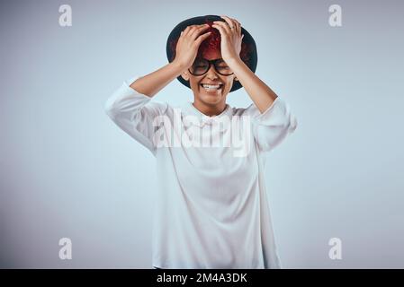 Le bonheur vous semble magnifique. Photo studio d'une belle jeune femme portant un chapeau sur fond gris. Banque D'Images