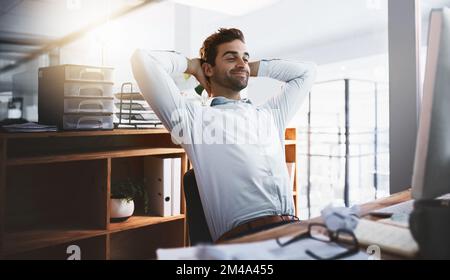 Les délais sont faits, maintenant je peux me reposer. un jeune homme d'affaires prend une pause tout en travaillant tard sur un ordinateur dans un bureau. Banque D'Images