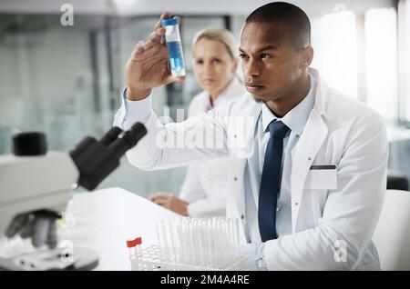 Ce pourrait être le seul... un beau jeune scientifique masculin testant un échantillon tout en faisant des recherches dans son laboratoire. Banque D'Images