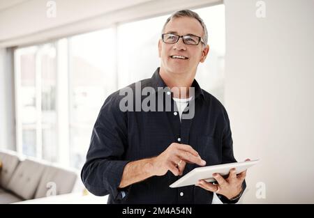 Quelle bénédiction la technologie mobile est devenue. un homme mature utilisant une tablette numérique à la maison. Banque D'Images