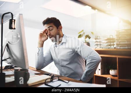 Combien de temps ai-je besoin d'être ici. un jeune homme d'affaires semble épuisé alors qu'il travaillait tard sur un ordinateur dans un bureau. Banque D'Images