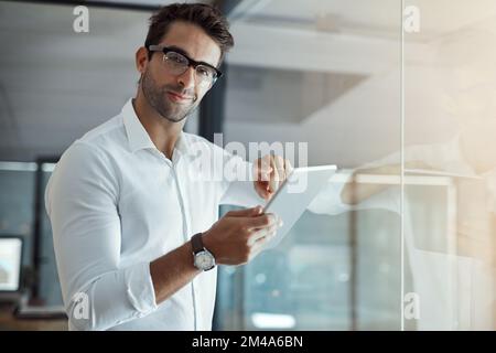 Rien de moins que le succès. Portrait court d'un jeune homme d'affaires beau travaillant sur sa tablette numérique au bureau. Banque D'Images