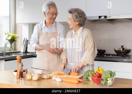 Joyeux couple chinois senior cuisine dans la cuisine Banque D'Images