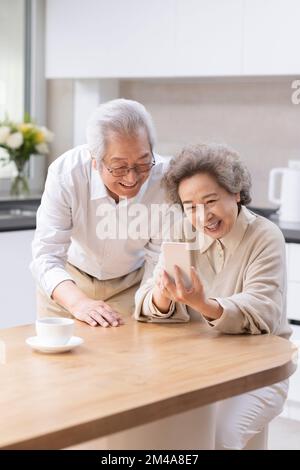 Couple chinois senior utilisant un smartphone à la maison Banque D'Images