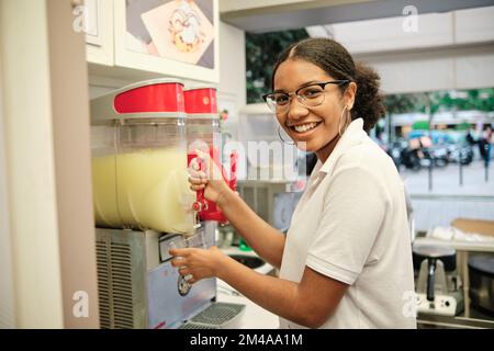 Employé souriant servant un citron d'un distributeur de drinks Banque D'Images