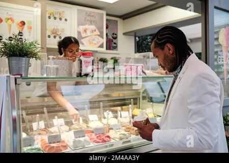 Client achetant une terrine de crème glacée dans un magasin Banque D'Images