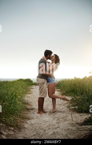 Le baiser qui scelle deux âmes. un jeune couple passe une journée romantique à la plage. Banque D'Images