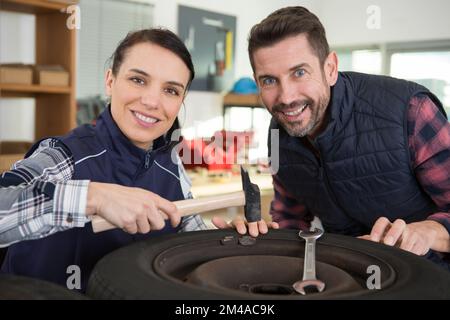 deux mécaniciens vérifiant la commande d'équilibre des roues à l'atelier automatique Banque D'Images