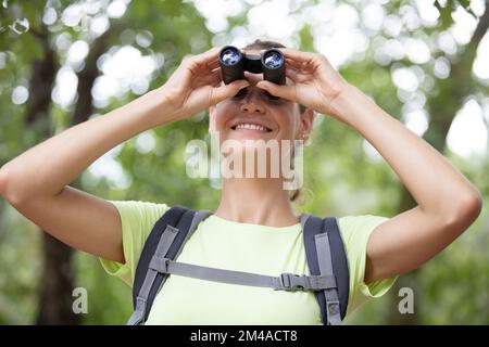 belle randonneur femelle regardant à travers binoculaire dans la forêt Banque D'Images