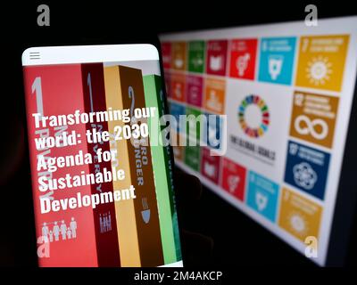 Personne tenant un téléphone portable avec le site Internet des objectifs de développement durable de l'ONU (ODD) sur l'écran devant le logo. Concentrez-vous sur le centre de l'écran du téléphone. Banque D'Images