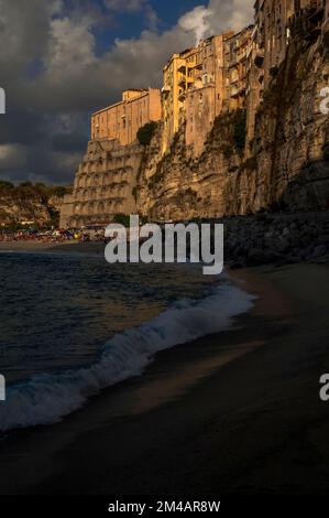 Les ombres assombrissent la mer Tyrrhénienne et dégrissent la plage de Convento tandis que les vacanciers profitent du soleil fin août, sous la ville historique de Tropea, sur la Costa degli Dei (côte des dieux), dans l'ouest de la Calabre, dans le sud de l'Italie. Banque D'Images