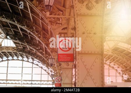 St. Petersbourg, Russie - 07.11.2022: Intérieur de la gare de Vitebsk, sunflare. Signe d'avertissement vertical rouge, traduction : ne pas sauter du plateau Banque D'Images