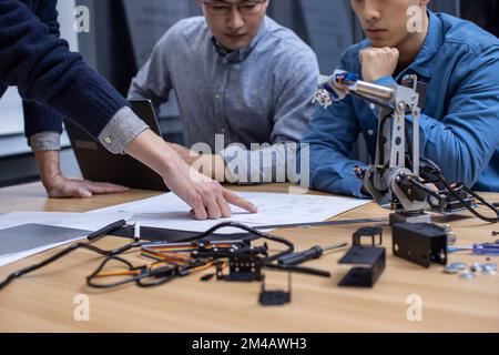 Des designers chinois confiants vérifient un bras robotique Banque D'Images