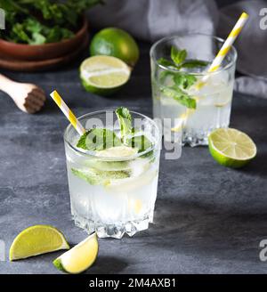 deux verres de mojito de limonade avec des tranches de lime et de menthe sur fond gris . photo sombre. Macro et gros plan Banque D'Images