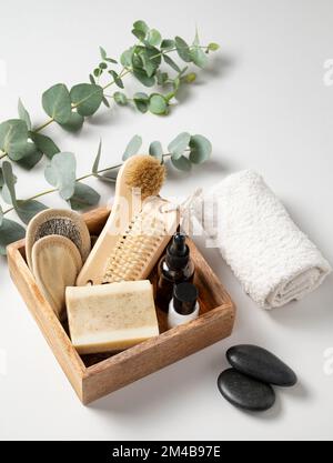 boîte en bois avec cosmétiques biologiques, crème, éponges, brosse, savon et pierre de massage sur fond blanc. Le concept de spa et de bien-être. Banque D'Images