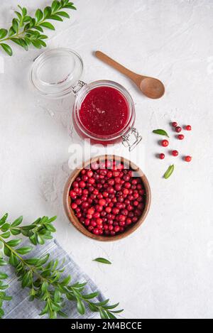 Concept Flat Lay avec confiture maison de mûres de lingonyère et de cowberry de forêt dans un bol sur table blanche avec serviette bleue. Image de la vue de dessus Banque D'Images