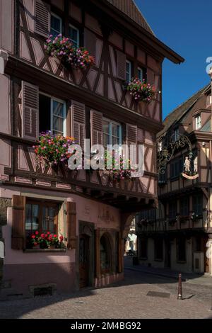 Un pèlerin tenant un personnel s'avance vers une maison typiquement alsacienne à pans de bois sur le panneau peint de la maison accroché d'un coin de la Maison au Pèlerin ou de la Maison du Pilgrim, construite en 1571 entre la Grand rue et la place de l'ancienne Douane (place des douanes) à Colmar, Alsace, Grand est, France. Banque D'Images