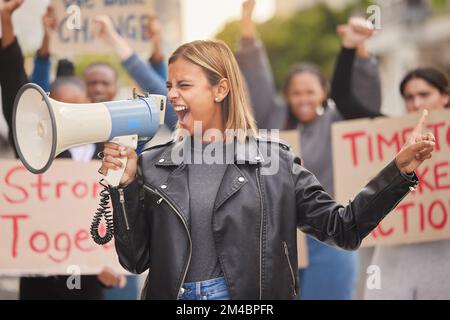 Protestation, manifestation et femme au mégaphone dans la ville criant pour la justice, la liberté et l'égalité. Liberté d'expression, droits de l'homme et foule de personnes Banque D'Images