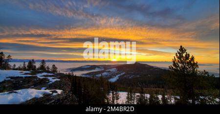 Photo panoramique d'une montagne, d'arbres et de neige sous le ciel magique bleu et orange vif Banque D'Images