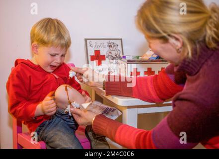 Pays-Bas, Arnhem; mère met de l'iode sur le genou blessé de son fils qui pleure. Banque D'Images