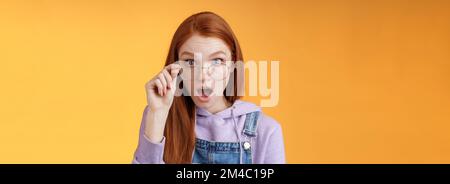 Choc impressionné collègue redhead entendre les dernières rumeurs intimes lâcher mâchoire regarder plein l'incrédulité de l'appareil photo confus les lunettes de contact semblent incertains la vérité mentir Banque D'Images