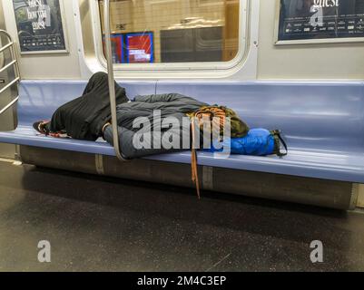 Un homme sans domicile dort sur un train E Line de métro à New York le dimanche, 18 décembre 2022. (© Richard B. Levine) Banque D'Images