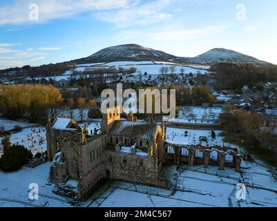 Prise de vue aérienne de l'abbaye de Melrose et des Eildons avec une couche de neige et de gel au coucher du soleil, par une belle journée d'hiver en décembre. Banque D'Images