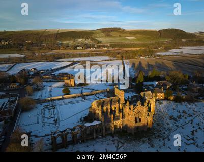 Photo aérienne de l'abbaye de Melrose et de la maison du Commenator avec une couche de neige et de gel au coucher du soleil, le jour d'hiver de décembre. Banque D'Images