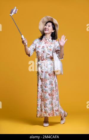 Une femme chinoise joyeuse prend le selfie avec un smartphone Banque D'Images