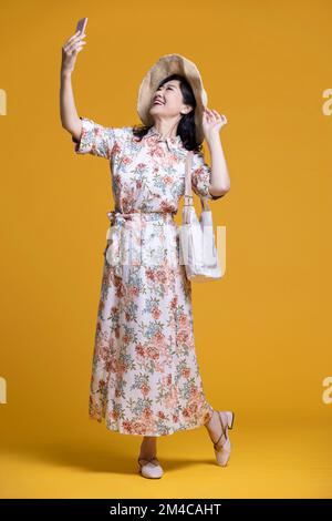 Une femme chinoise joyeuse prend le selfie avec un smartphone Banque D'Images
