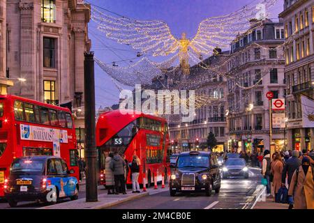 Regent Street, Londres - une foule de clients qui se prominent entre les grands magasins éclairés et le trafic de vacances sous les lumières de Noël Banque D'Images